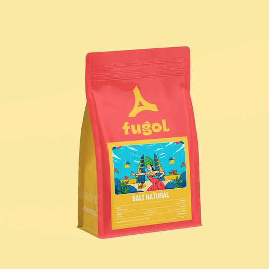 A red stand-up pouch of Fugol Bali Natural coffee on a solid pale yellow background. The packaging features a yellow logo and a colorful illustration of a beach scene on the front label.